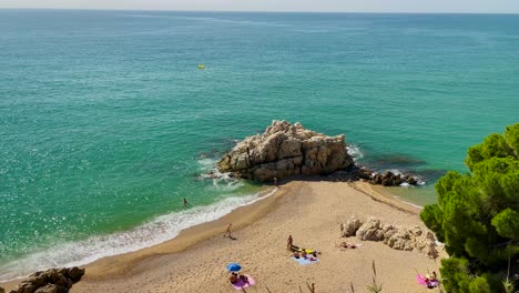 Cala-Roca-Grossa-Día-Soleado-De-Verano-Turismo-Europeo-Mediterráneo-Paraíso-Playa-Vista-Aérea-Desde-Drone-Contraste-Con-Arena-De-Roca-Y-árboles-Verdes