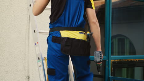 technician holds drill climbing ladder