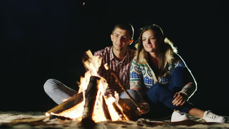 Hombre-Y-Mujer-Relajante-Noche-Alrededor-De-La-Fogata-Asar-Malvaviscos-En-Fuego-De-Palos