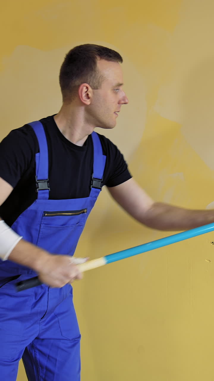 Man painting wall at home. Portrait view of painter hands painting the wall