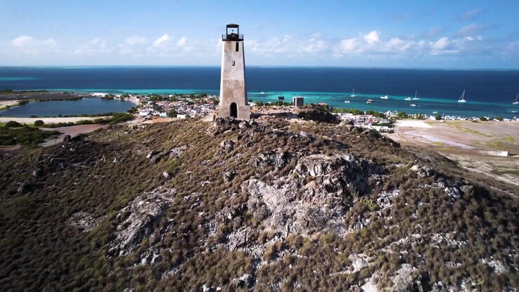 Un faro sulla costa su una collina rocciosa che domina una vivace città costiera, vista aerea