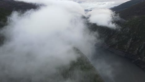 volando a través de las nubes sobre un lago, un bosque y montañas en españa