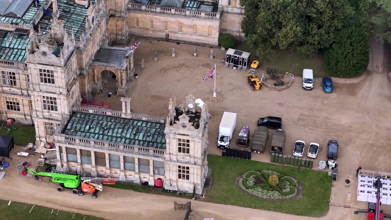 Vista aerea della casa di campagna Mentmore Towers, con veicoli da set cinematografico parcheggiati sui terreni di una sontuosa tenuta.