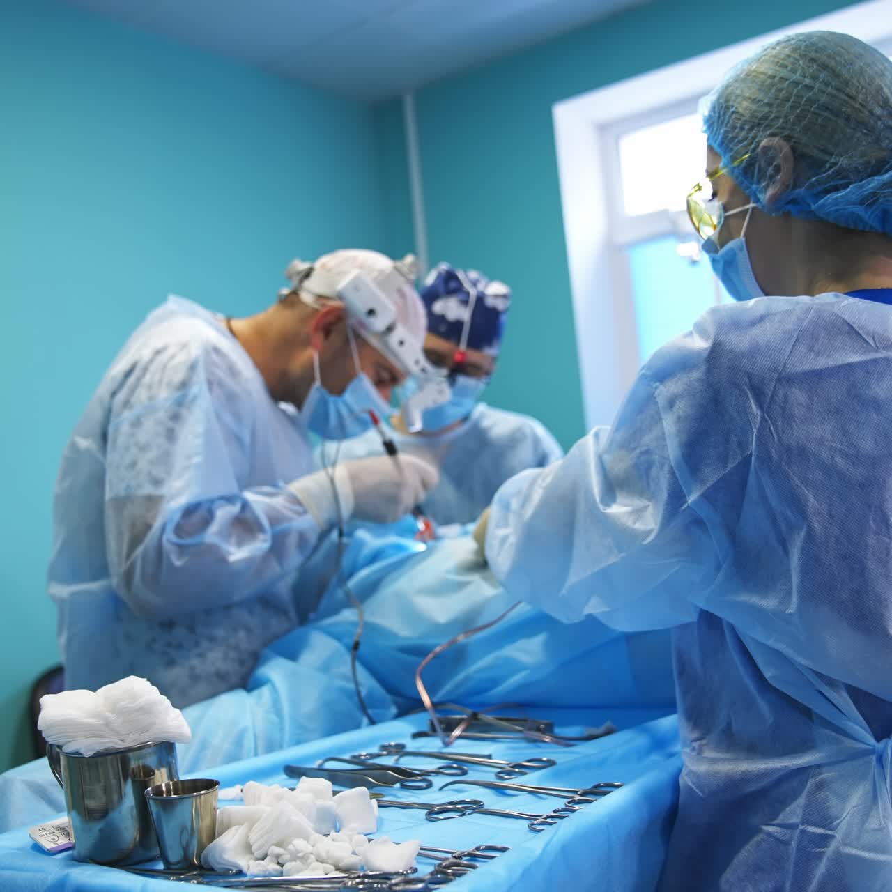 Nurse helping the surgeons during the operation. Female assistant takes the used sponges away. Blurred backdrop