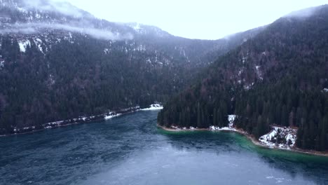 aerial view of a stunning frozen lake under the alps with the islands in snow