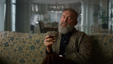 old business man sitting sofa with whiskey glass. portrait senior gentleman