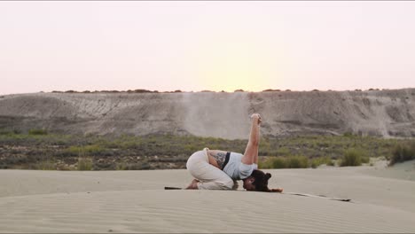 joven instructor de yoga en una colina de arena haciendo una rutina matutina durante el amanecer