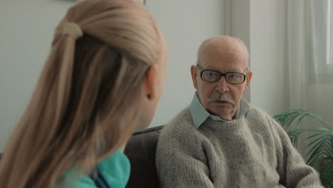 elderly man talking with young caring nurse