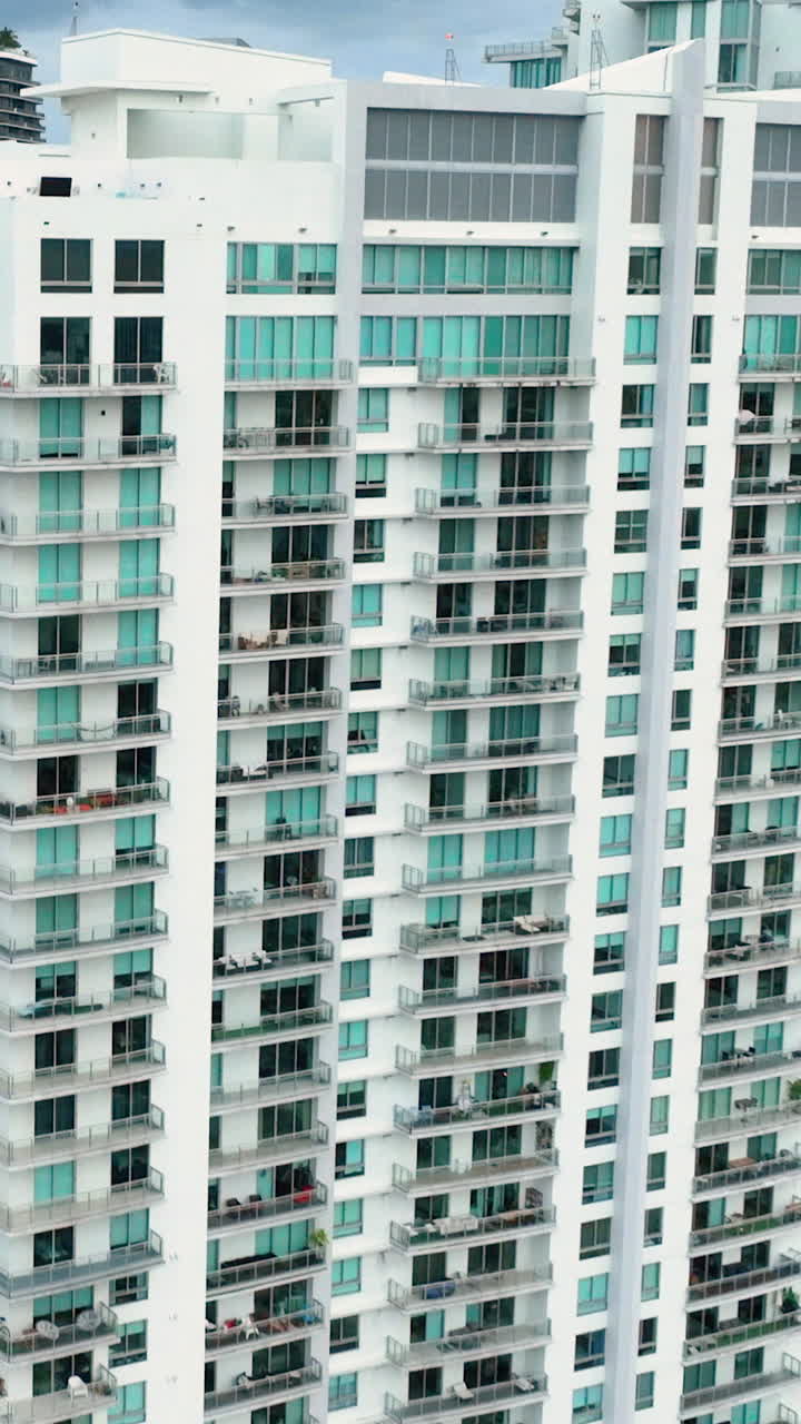 Facade of high multi-story building with balconies and windows. Skyscraper buildings in downtown district of Miami Brickell. American megapolis. Vertical video