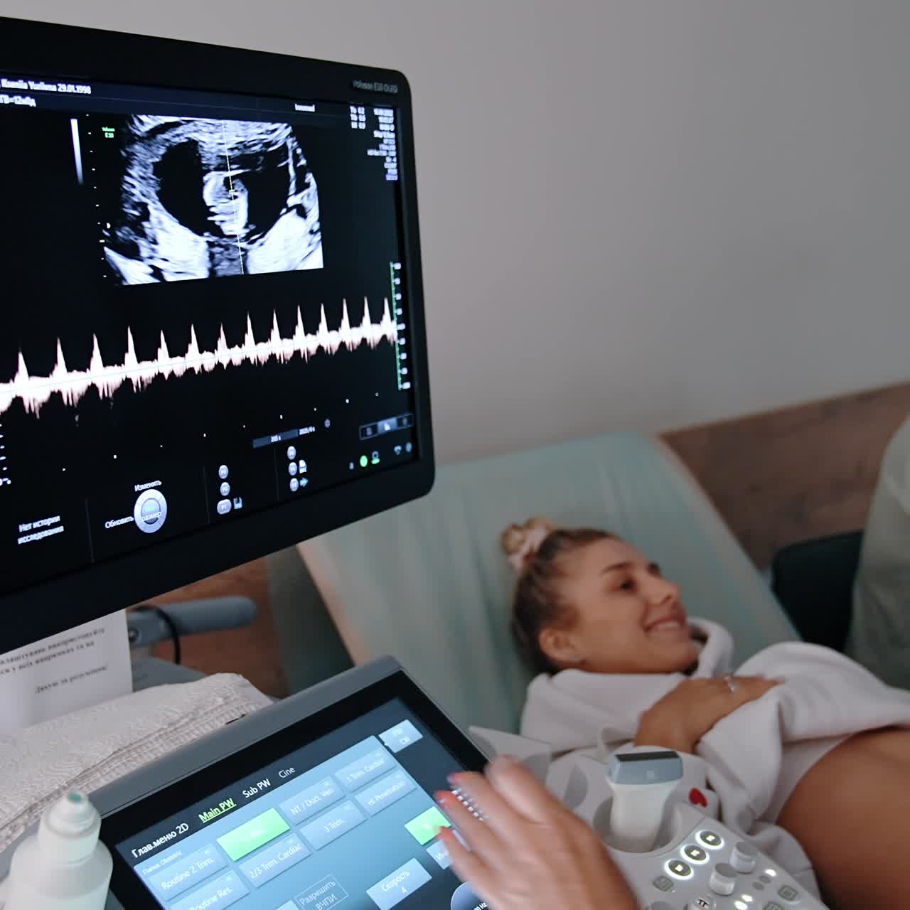 Monitor of ultrasound machine shows the baby image in mom's abdomen. Expecting couple at ultrasonic check up