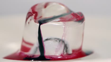 pintura en cámara lenta cayendo sobre un cubo de hielo filmado en macro
