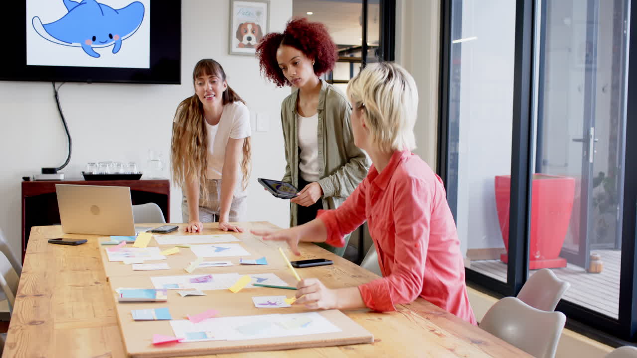 Collaborating on creative writing project, three women discussing ideas at office table