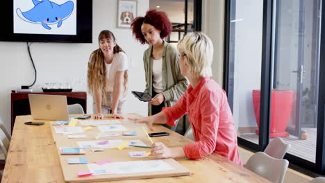 collaborating on creative writing project, three women discussing ideas at office table