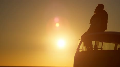silhouette of romantic couple sitting on roof of van 4k