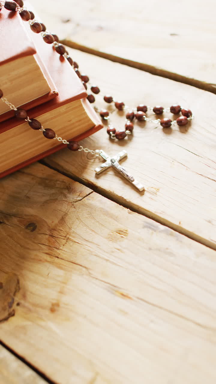 Vertical video of books and rosary on wooden background with copy space