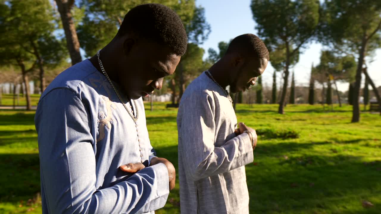 Two African men praying in a park