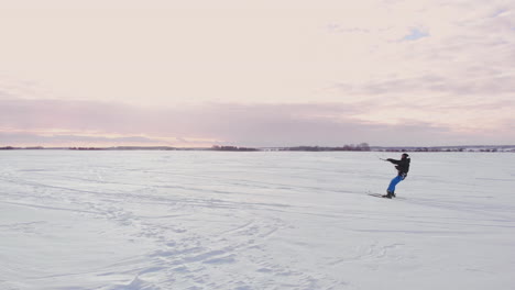 4K-aerial-winter-extreme-sport-snow-kiting-competition-race-with-different-colorful-snow-kites,-ski,-snowboarders-over-the-ice-lake-in-front-of-city-at-blizzard-and-snow-weather-from-drone