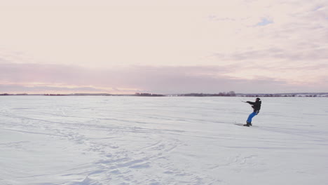 4k aerial winter extreme sport snow kiting competition race with different colorful snow-kites, ski, snowboarders over the ice lake in front of city at blizzard and snow weather from drone