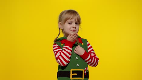 Shy-shamed-child-girl-in-Christmas-elf-Santa-helper-costume-posing-looking-camera,-blows-air-kiss