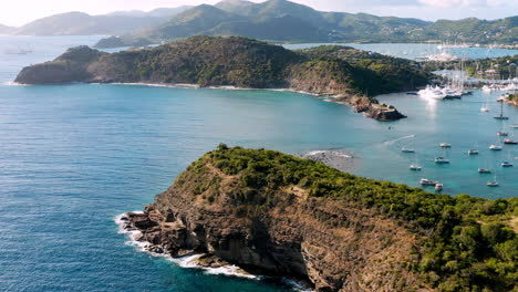 Sonnige-Luftaufnahme-Des-Englischen-Hafens-In-Antigua,-Karibik-Mit-Blick-Auf-Yachten,-Segelboote,-Marina,-Bucht-Und-Klippen