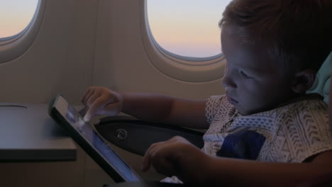 Nahaufnahme-Eines-Kleinen-Jungen,-Der-Im-Flugzeug-Mit-Dem-Touchpad-Auf-Dem-Tisch-Spielt