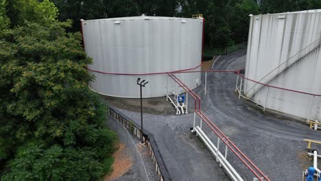 petroleum and fuel storage in suburb of american town. trees in summer. pipelines connecting tanks. aerial view