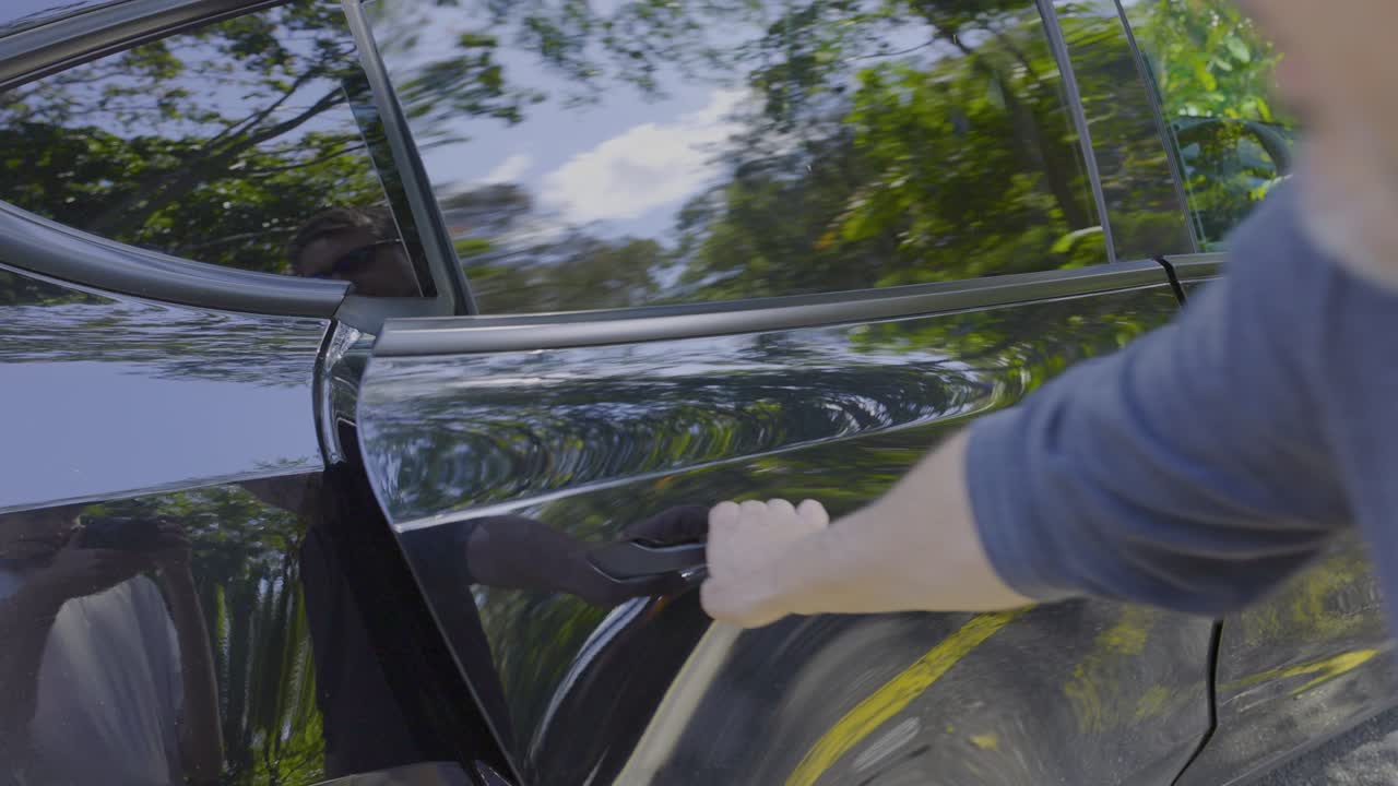 Persona che apre la portiera di un'auto Tesla