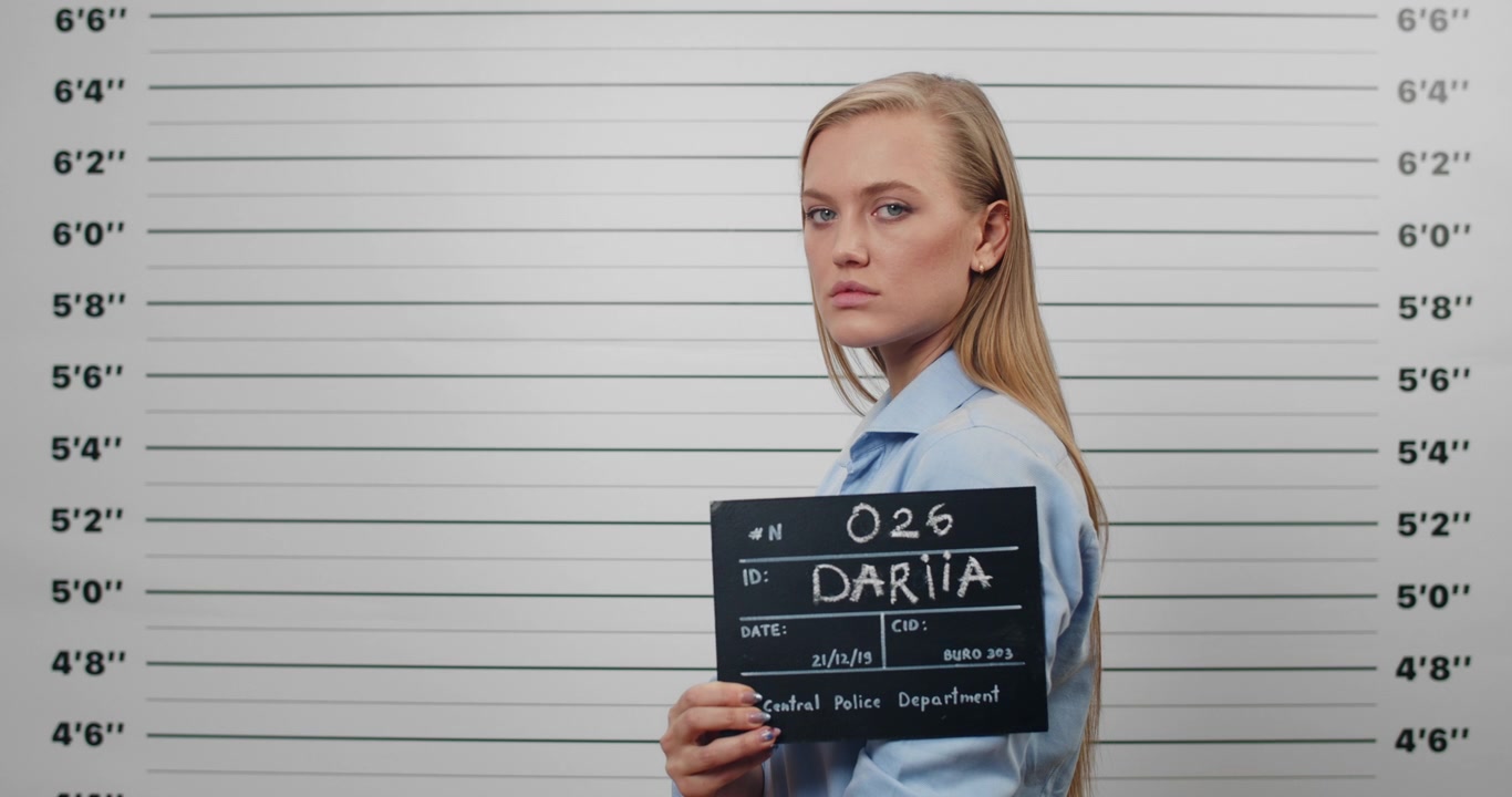 Young Woman Holding Mugshot Board in Police Station