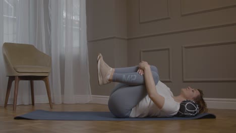 Caucasian-Woman-On-Yoga-Mat-Lifting-Left-Leg-In-Air