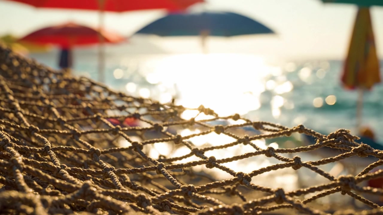 Splendida giornata in spiaggia: luce solare che danza sull'acqua e ombrelloni colorati si ergono alti sopra una rilassante amaca a rete in riva al mare.