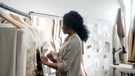 woman designer taking a cloth and smiling cheerfully at camera in the designing studio