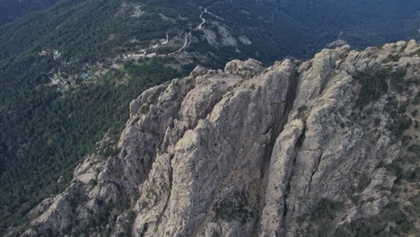 man standing on mountain overlooking lush green forest