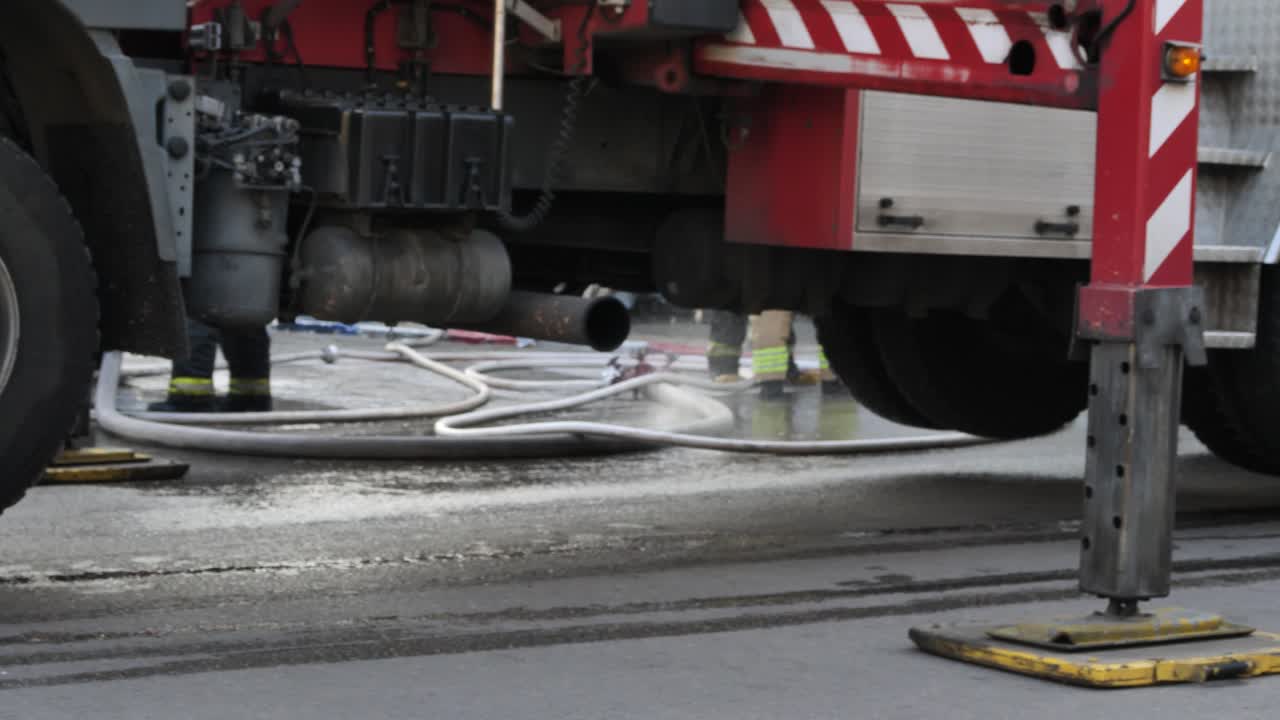 camión de bomberos levantado, manguera rociando agua, accidente, acción de bomberos en la calle
