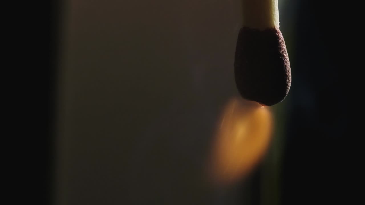 foto macro de la cabeza del fósforo que va a lo largo de la banda de fricción en la caja de fósforos y se enciende con un fondo oscuro