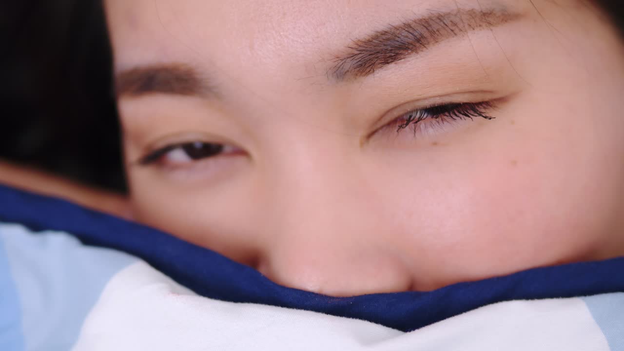 아름 다운 여성 웃 고 카메라와 담요로 덮여 침대에 사랑 스러운 거짓말을 보고