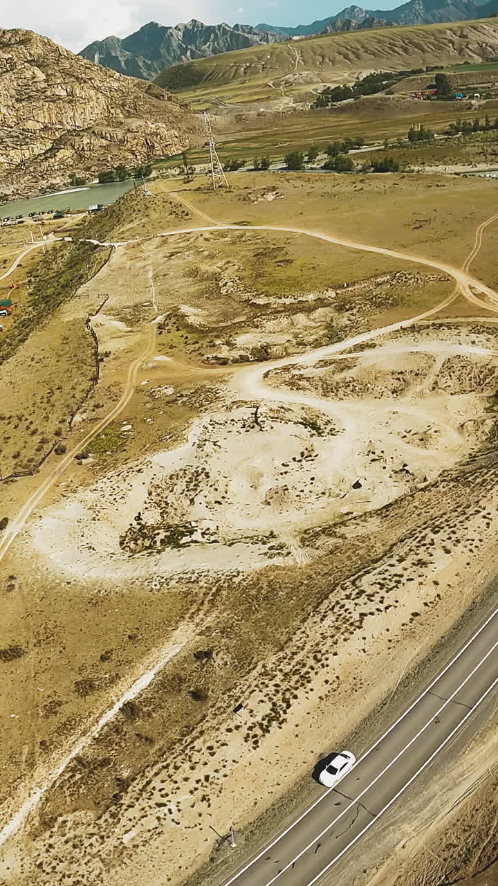 el río serpenteante serpentea a través del valle. las orillas adyacentes a la carretera que conducen al campamento turístico anidado en el abrazo de las tierras altas. los acantilados altísimos