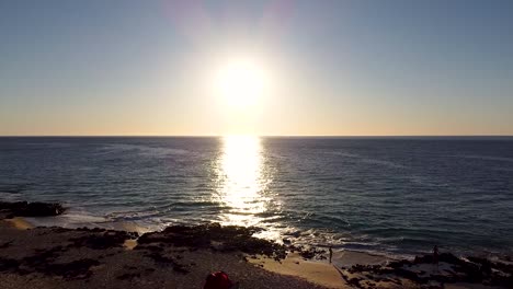 Aerial---drone-shot-of-a-tent-on-a-beach-at-sunset