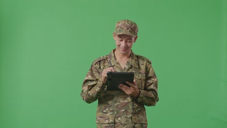 asian man soldier taking note on a tablet while standing in the green screen background studio