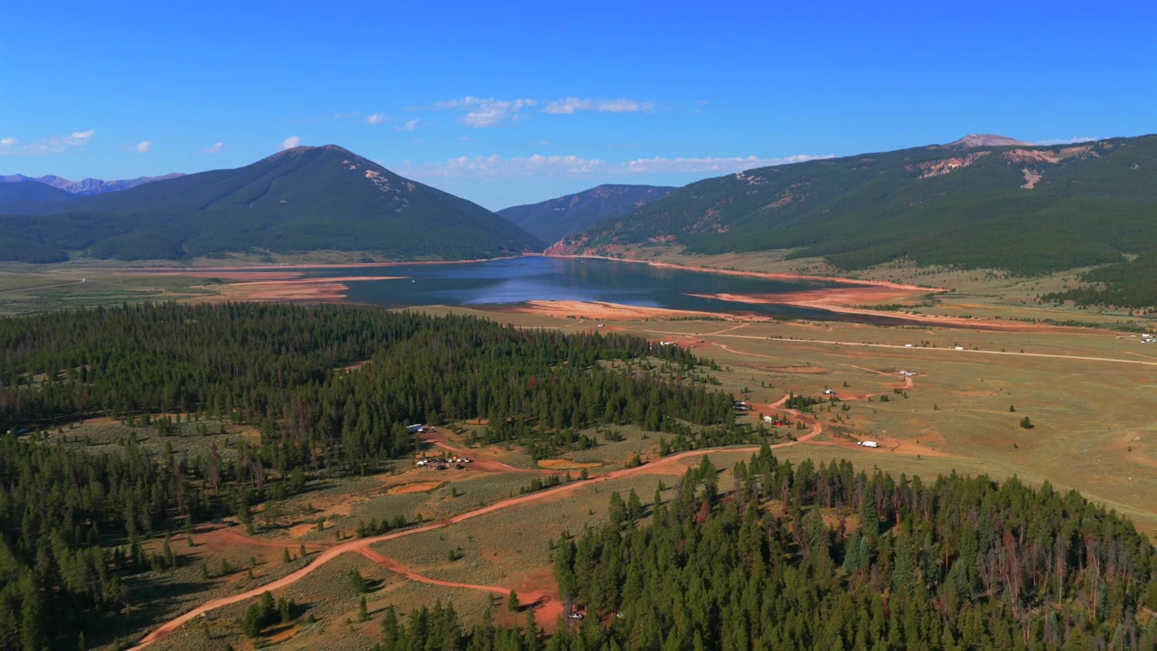 Diga della Marina del bacino idrico di Taylor Park, basso livello del lago, ripresa aerea con drone, Almont Colorado, dal campeggio Lakeview Campground, Contea di Gunnison, mattina estiva soleggiata, cieli blu, con Park Cone e la Catena Sawatch sullo sfondo, ripresi in salita.