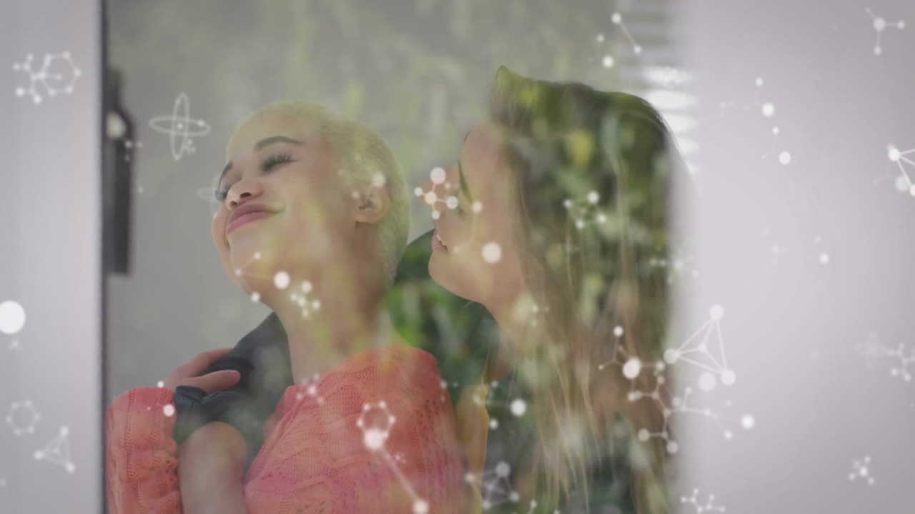 Two women embracing indoors, displaying molecular overlay highlighting science education theme