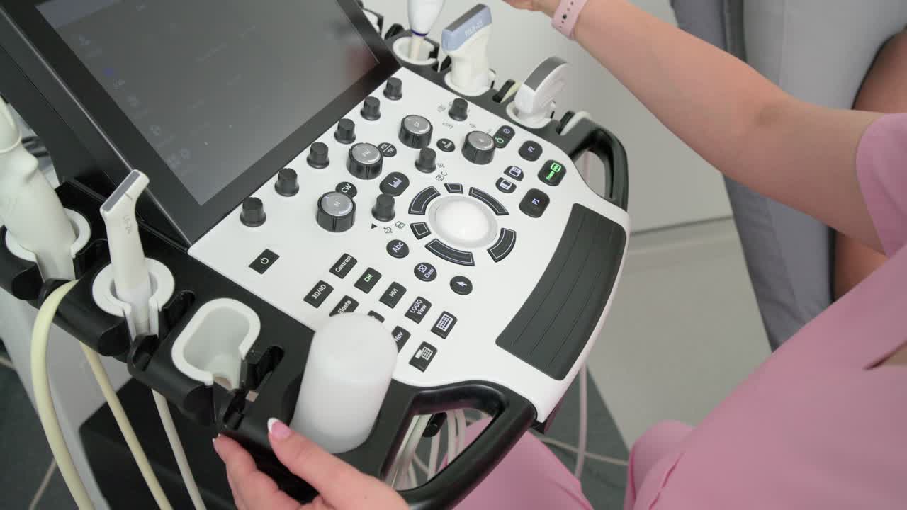 Hendel vastgrijpend, technicus draait trackball, stelt knoppen af, tilt sonde op om scan in te stellen op onderzoekstafel