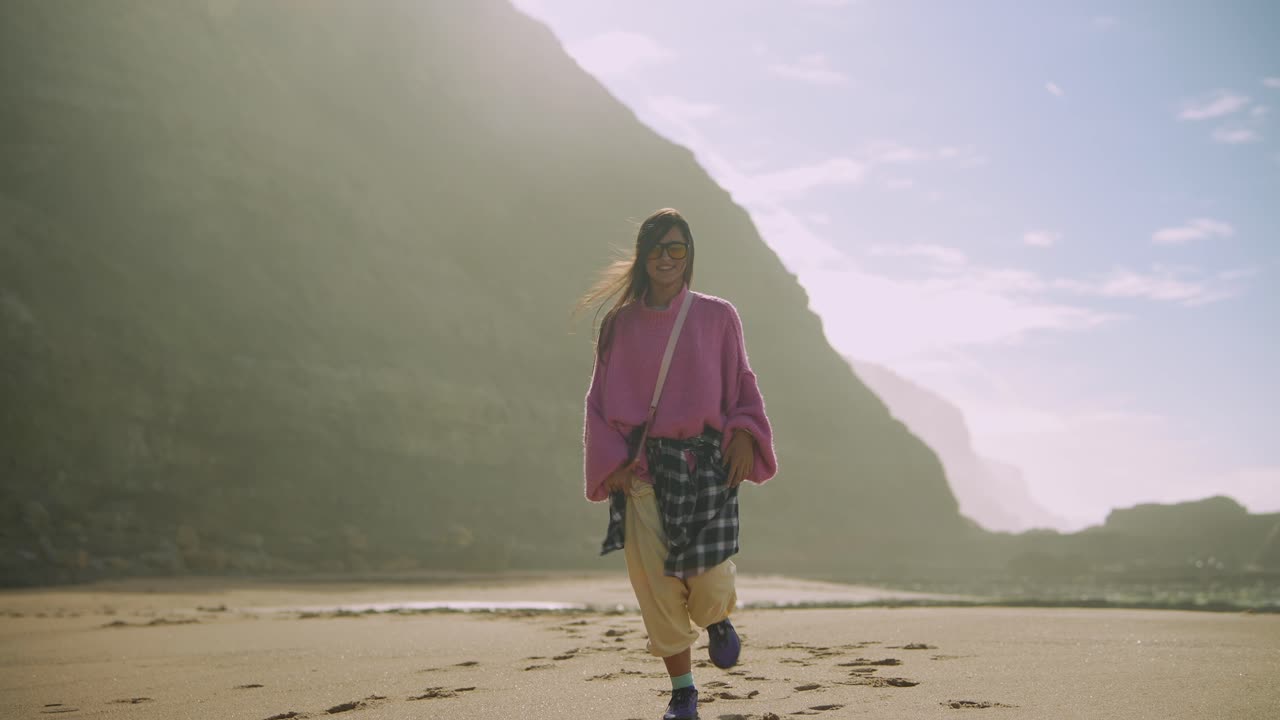 Giovane donna spensierata che corre e cammina su una spiaggia panoramica