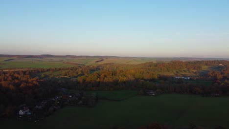 autumn aerial view over english countryside with small quaint village as sun sets over fields - drone shot in dorset uk
