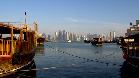 doha modern city skyline day shot, qatar, middle east. view on doha skyscrapers with traditional wooden qatar boats at corniche broadway