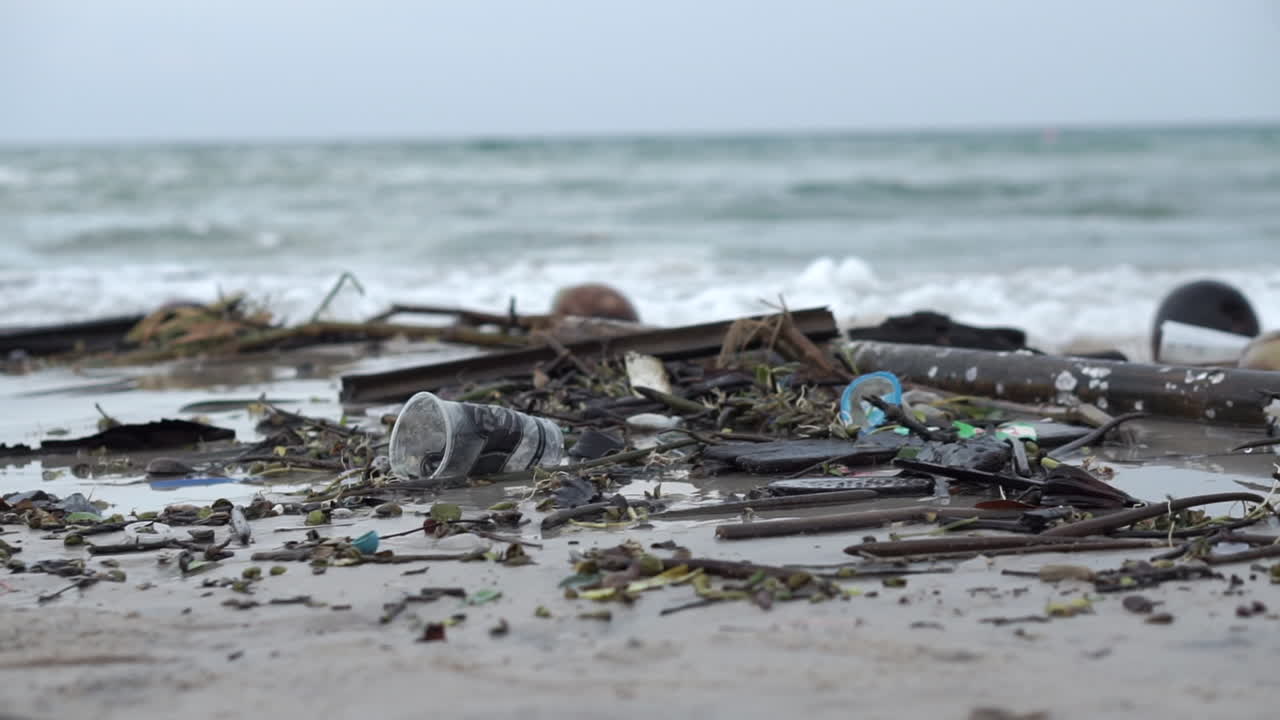 Very polluted and dirty beach full of plastic and debris on the sand and in the water along the coast