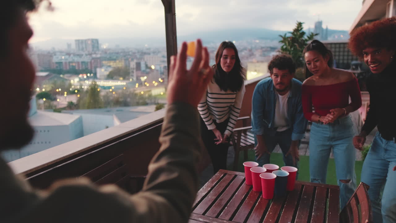 A group of friends playing beer pong on a rooftop