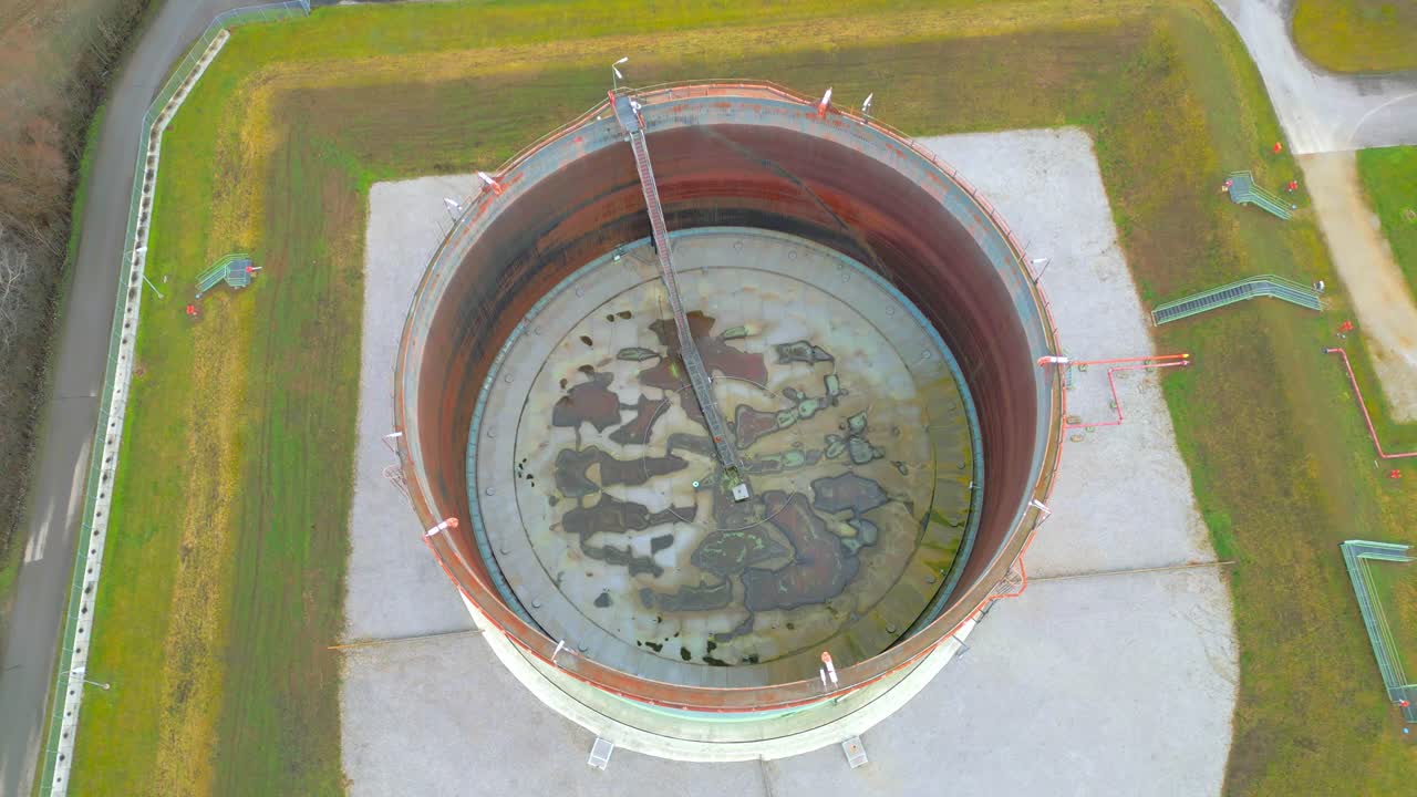 기름 저장소에 떠 있는 지붕이 있는 녹슨 기름 저장 탱크