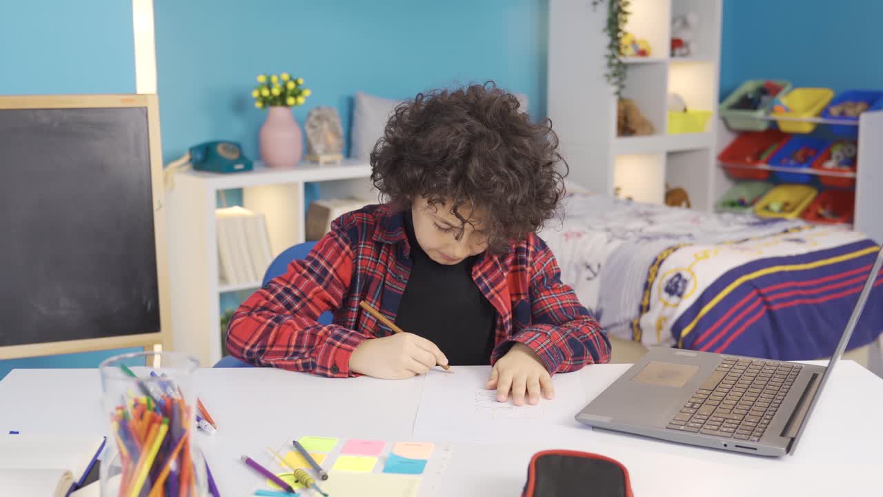 Successful boy draws at table in children's room.