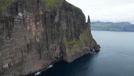 Toma-Aérea-Hacia-Atrás-Que-Muestra-Escarpados-Acantilados-Rotos-En-La-Isla-De-Vagar-Durante-Un-Día-Nublado-Místico,-Islas-Feroe