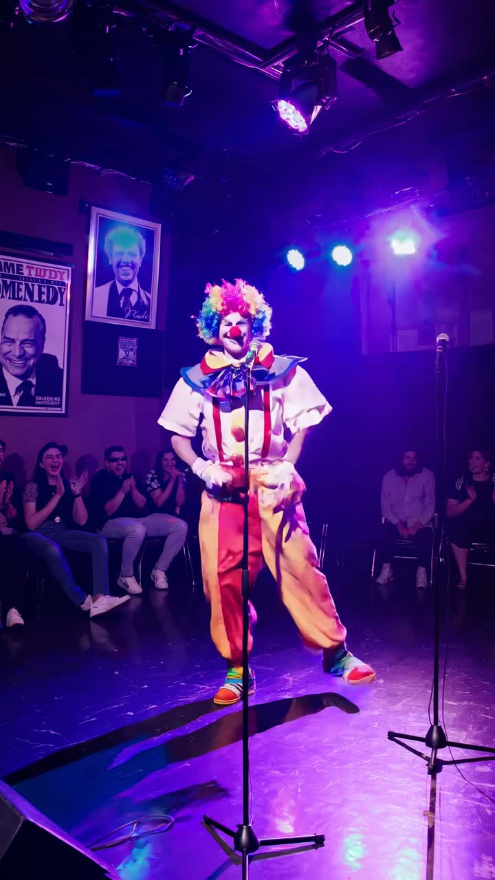 A clown performs on stage under green lights, captured from a low-angle, creating a dynamic video